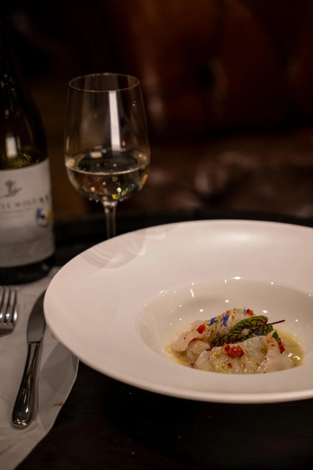 Savoury tasting-menu course with wine at a dining table